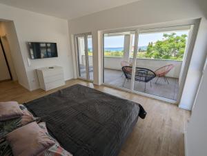 1 dormitorio con 1 cama y balcón con mesa y sillas en Villa SunSet, en Privlaka