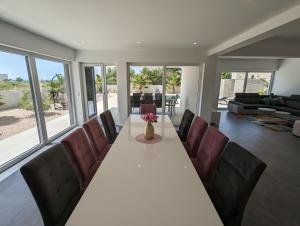a dining room with a long table and leather chairs at Innova TravelVir - Villa SunSet in Privlaka