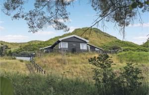 una casa en un campo con una colina en el fondo en Amazing Home In Blokhus With House Sea View, en Blokhus
