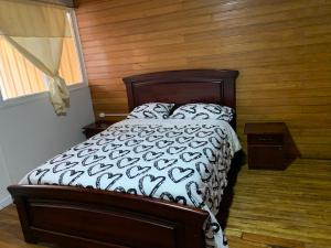 1 cama en un dormitorio con pared de madera en My House in Macas Penhouse en Macas