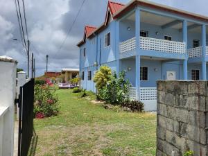 a blue house with a yard in front of it at OceanView Villa in Buccoo