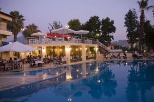 a large swimming pool with people sitting around a restaurant at Grand Cnr Hotels in Fethiye