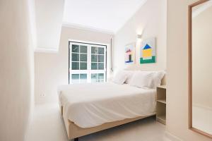 um quarto branco com uma cama e uma janela em Timeless Loft at the Village em Ericeira