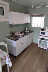 una pequeña cocina con armarios blancos y fregadero en Studio Punat 5410a, en Punat