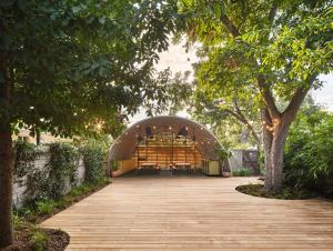 a wooden walkway leading into a building with trees at The Carpenter Hotel in Austin
