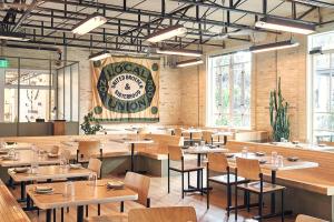 a restaurant with tables and chairs and a sign on the wall at The Carpenter Hotel in Austin