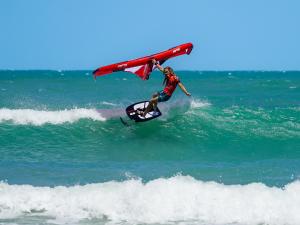 a man riding a wave on a surfboard in the ocean at VentoVinte Beach Club in Flecheiras