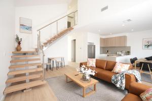 a living room with a couch and a staircase at Powder Peaks in Jindabyne