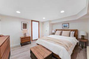 a white bedroom with a large bed and a dresser at Gulf Island View Suite in Chemainus