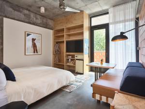 a bedroom with a bed and a desk and a tv at The Carpenter Hotel in Austin