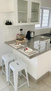 una cocina con armarios blancos y taburetes blancos en Stay in Style en Durban