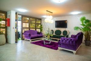 BLISS BOUTIQUE HOTEL BOGOTA في بوغوتا: غرفة معيشة مع أرائك أرجوانية وتلفزيون