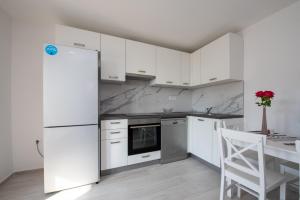 La cuisine est équipée de placards blancs et d'un réfrigérateur blanc. dans l'établissement Apartments with a parking space Split - 21525, à Split