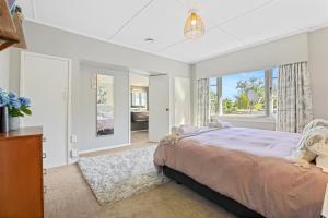 a bedroom with a large bed and a large window at Redwoods Retreat in Rotorua