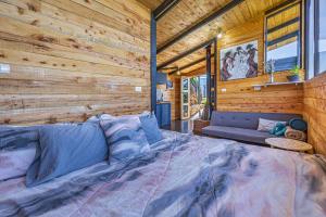 Cama grande en habitación con pared de madera en Tiny House Jaulares, en Rivas