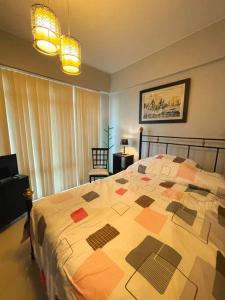 a bedroom with a bed with a quilt on it at Lovely & Stylish 1BR in Mckinley Hill with View in Manila