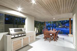 a kitchen with a stove and a table with chairs at 20 Wesley Court, Noosa Heads in Noosa Heads