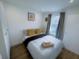 um quarto com uma cama com almofadas amarelas e uma janela em (ZONE 2) STYLISH 2 BED FLAT IN THE HEART OF LEWISHAM em Londres