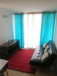 a living room with a black leather couch and blue curtains at Departamento Peñuelas Sol Marina III La Serena - Coquimbo in Coquimbo