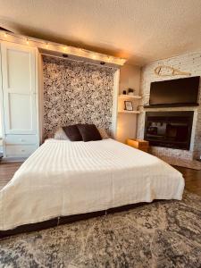 1 dormitorio con 1 cama blanca grande y chimenea en Condo loft ski in - ski out à Stoneham en Stoneham