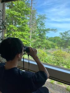 un hombre con una cámara mirando por la ventana de un tren en Hororo Style, en Shimo-setsuri