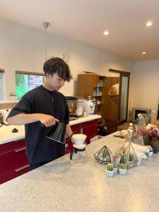 a man is standing in a kitchen preparing food at Hororo Style in Shimo-setsuri