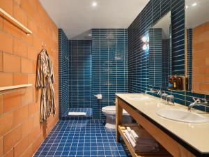 a blue tiled bathroom with a toilet and a sink at The Carpenter Hotel in Austin