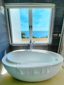 a bath tub in a bathroom with a window at Kenting Ocean Paradise Resort in Hengchun