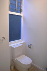 a white toilet in a bathroom with a window at U Suites on Webb in Wellington