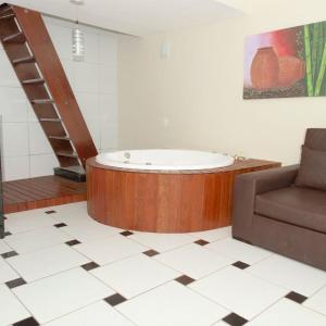 eine Badewanne in einem Zimmer mit einem Sofa und einer Treppe in der Unterkunft Hotel Arrecife dos Corais in Cabo de Santo Agostinho