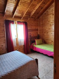 1 dormitorio con 2 camas en una cabaña de madera en Cabañas Celi en Esquel