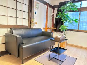 um sofá de couro numa sala de estar com uma mesa em -九条竹海- 和風丸々貸切一軒家 ベッドルーム3つ トイレ2つ 最大8人宿泊可 十条駅徒歩で5分 em Quioto