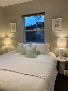 a bedroom with a large white bed with two lamps at Angaston Mews Apartments in Angaston