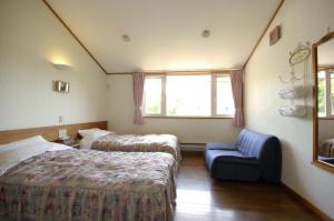 una habitación de hotel con 2 camas y una silla en Pension Field en Hokuto
