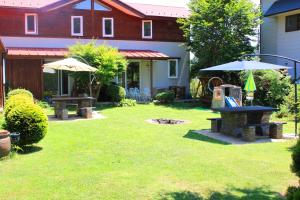 un patio con 2 mesas de picnic y sombrillas en Pension Field en Hokuto