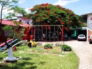 un parque infantil frente a un edificio con un árbol en Pousada Cirandinha Apart Hotel, en Itajaí