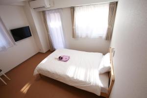 Un dormitorio con una cama blanca con una toalla rosa. en Connect Inn en Osaka