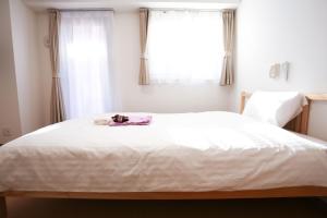 Un dormitorio con una gran cama blanca y una ventana en Connect Inn, en Osaka
