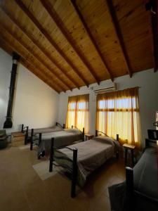 a room with three beds and windows and wooden ceilings at Hostel Bahía Ballenas in Puerto Pirámides