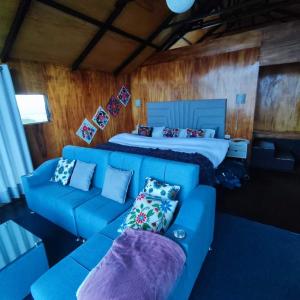 a living room with a blue couch and a bed at Uros Tikarani hotel in Puno