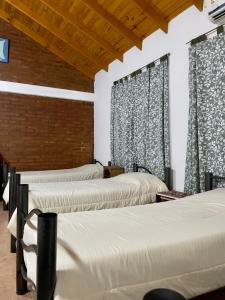 a group of three beds in a room with curtains at Hostel Bahía Ballenas in Puerto Pirámides