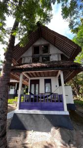 una casa con un porche frontal morado y un árbol en HAPPY DIVE RETREAT fka Ankermi Happy Dive, en Hitokalak