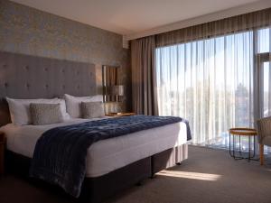 um quarto com uma cama grande e uma janela grande em Porters Boutique Hotel em Havelock North