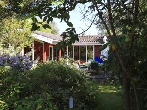 ein rotes Haus mit einer Veranda und einem Garten in der Unterkunft Holiday home Vordingborg XI in Vordingborg