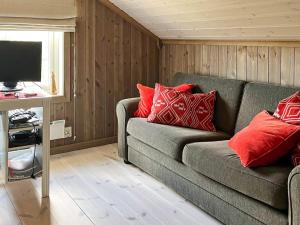 uma sala de estar com um sofá cinzento com almofadas vermelhas em Holiday home NESBYEN III em Nesbyen