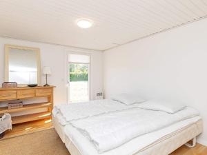 ein weißes Schlafzimmer mit einem Bett, einer Kommode und einem Spiegel in der Unterkunft Holiday home Karrebæksminde IX in Karrebæksminde