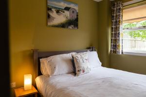sypialnia z białym łóżkiem z lampką i oknem w obiekcie The Apartment w mieście Bamburgh