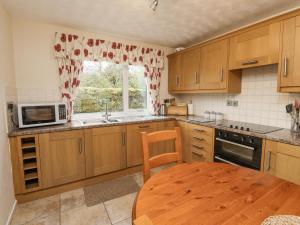 a kitchen with wooden cabinets and a table and a window at New Cottage in Wooler