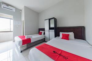 a bedroom with two beds with red pillows at RedDoorz Syariah near RS Hermina Sukabumi in Sukabumi