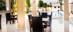 ディアニ・ビーチにあるUhai Vacationsのテーブルと椅子のあるレストラン、スイミングプールを提供しています。